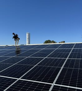 Commercial rooftop solar array under clear Oklahoma sky with a technician on the roof